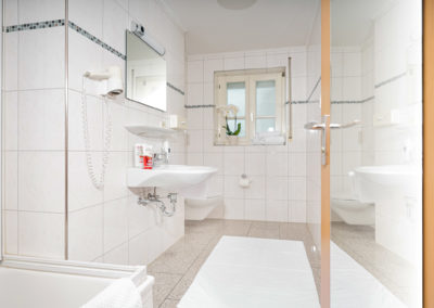 Badezimmer eines Doppelzimmers mit Waschbecken, Spiegel, Badewanne und WC | Apart Business Hotel