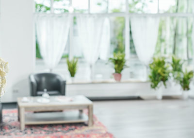 Helle Lobby mit weißem Blumenstrauß, Sitzecke und Pflanzen an den Fenstern | Apart Business Hotel