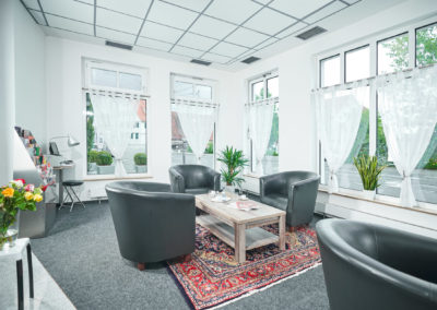 Sitzecke der Lobby mit schwarzen Ledersesseln, Couchtisch und Orientteppich vor großen Fenstern | Apart Business Hotel